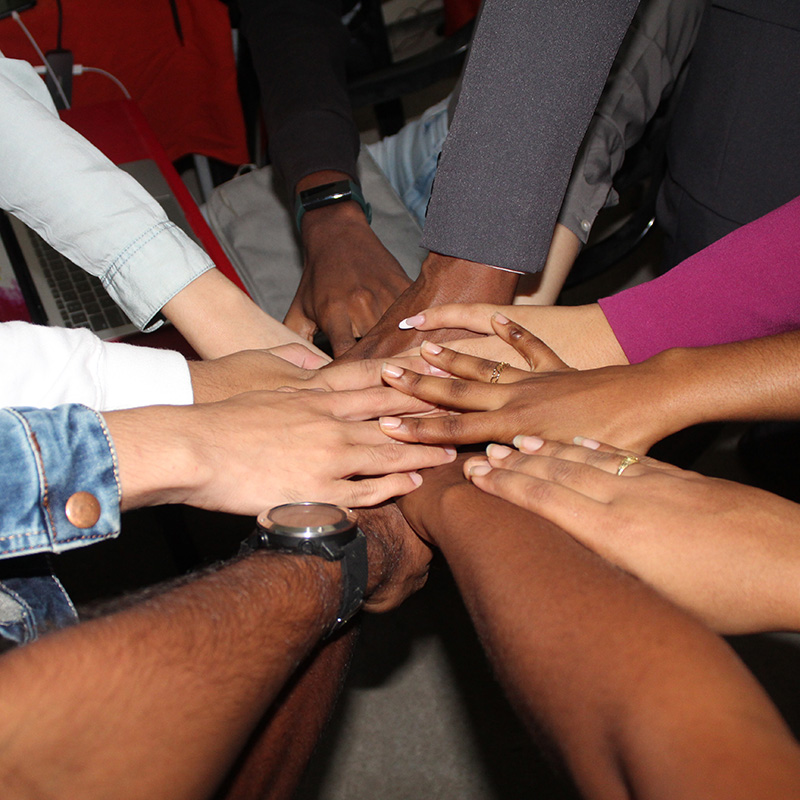 Photo of a group of people putting their hands together in a circle.