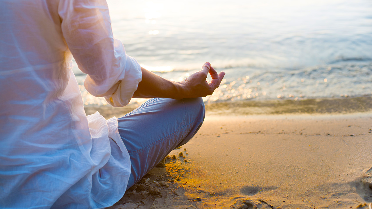 a client meditates on the shore, practicing what her wellness coach told her