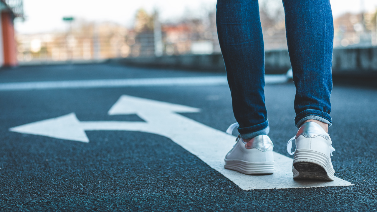 standing at a crossroads with white arrows on the ground, deciding which way to go