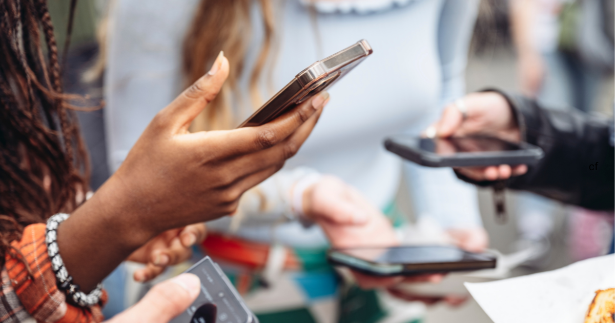 Group of friends checking their social media apps on their phones.