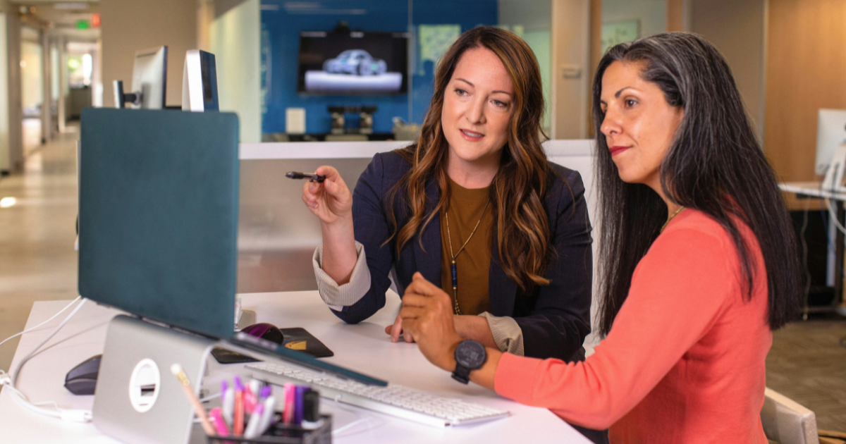 two women working on a business plan in front of a computer.